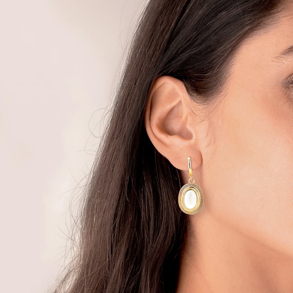 Woman wearing large white oval stone drop earrings