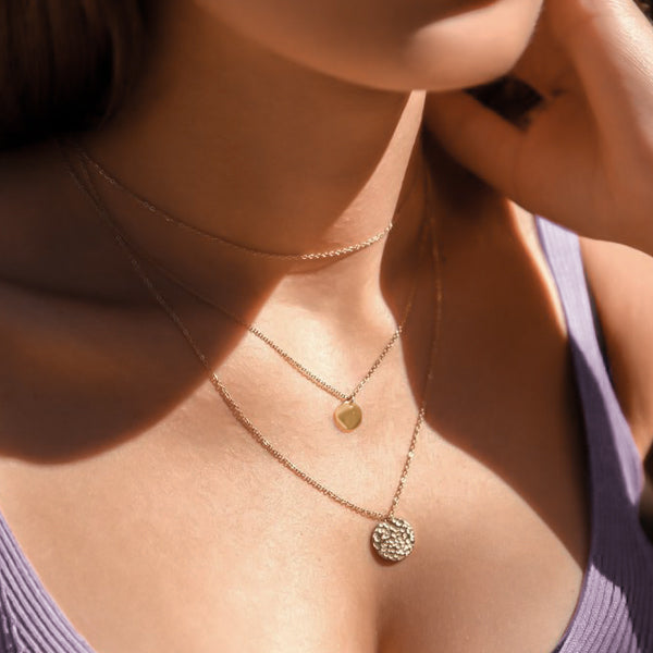 Woman wearing a gold layered coin pendant necklace set