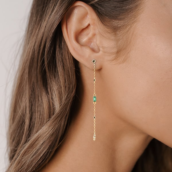 Woman wearing long gold drop chain earrings