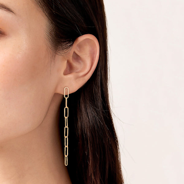 Woman wearing long gold oval link chain drop earrings