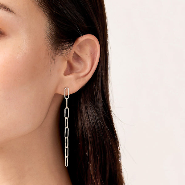 Woman wearing long silver oval link chain drop earrings