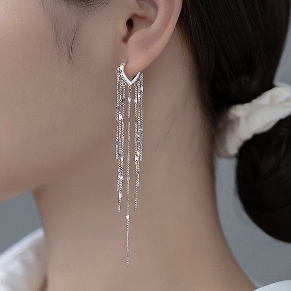 Woman wearing long silver tassel drop earrings