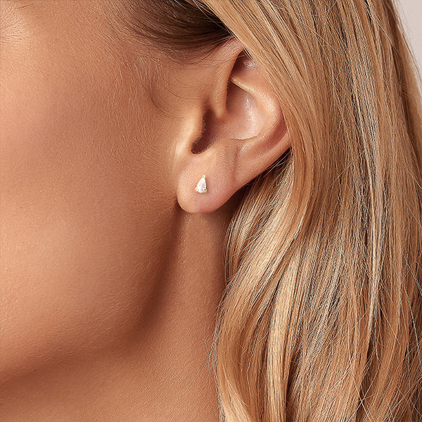 Woman wearing gold and clear white teardrop cubic zirconia mini stud earrings