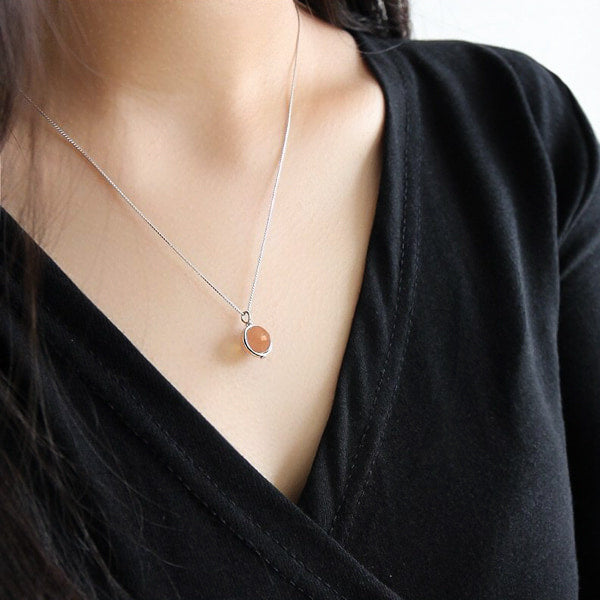 Woman wearing an orange moonstone pendant necklace