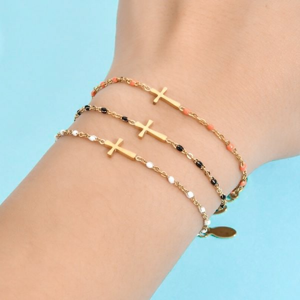 Woman wearing a gold cross bracelet with peach beads