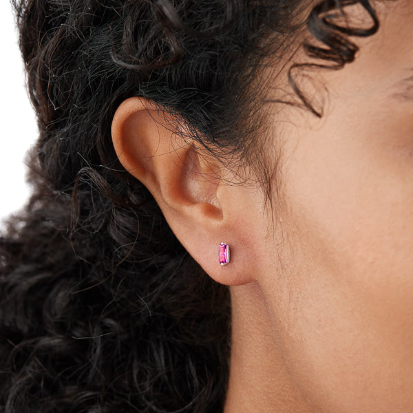 Woman wearing silver and pink mini baguette cubic zirconia stud earrings