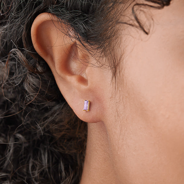 Woman wearing gold and purple mini baguette cubic zirconia stud earrings
