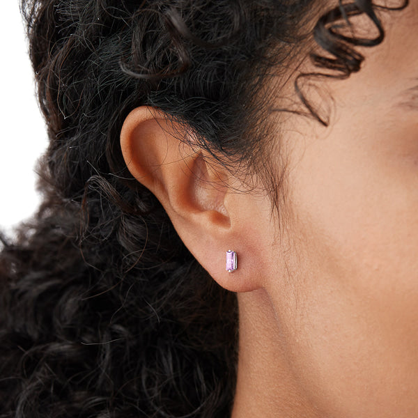 Woman wearing silver and light purple mini baguette cubic zirconia stud earrings