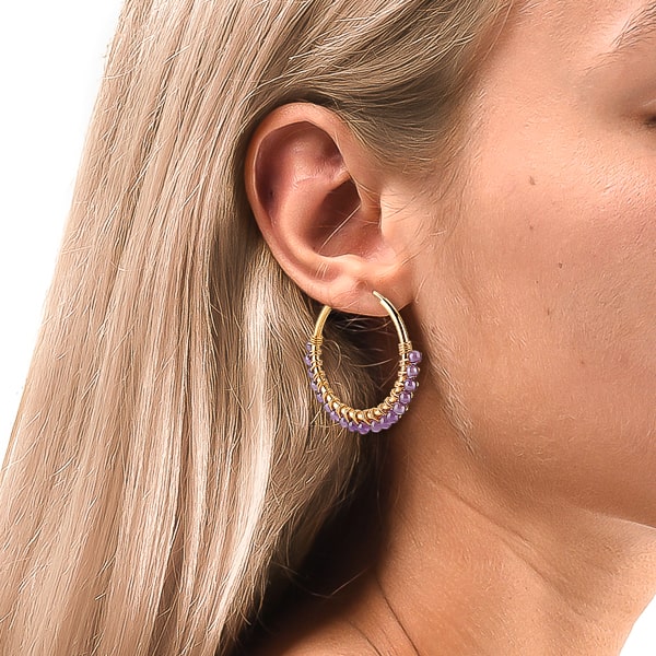 Woman wearing purple bead hoop earrings
