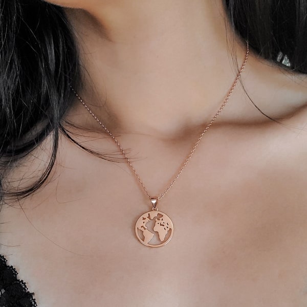 Woman wearing a rose gold world pendant necklace