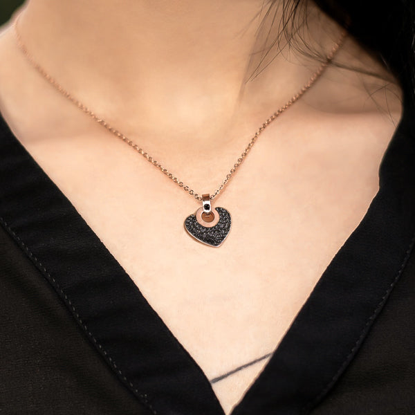 Woman wearing a black crystal heart pendant on a rose gold necklace