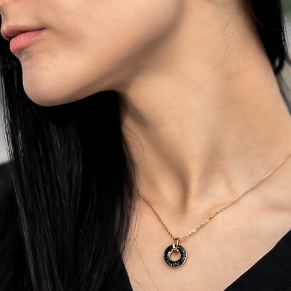 Woman wearing a black crystal ring pendant on a rose gold necklace