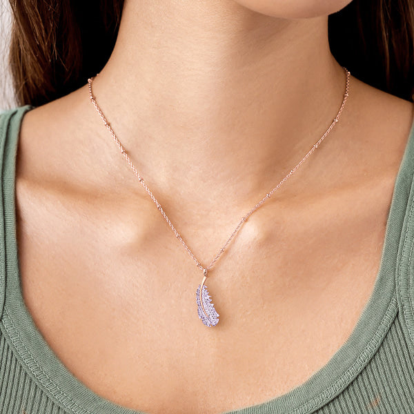 Woman wearing a rose gold crystal feather necklace