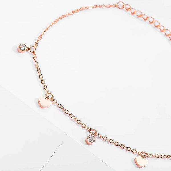 Rose gold love charm anklet with heart and crystal pendants close up