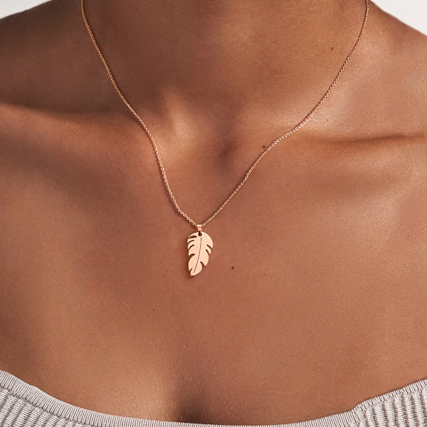 Woman wearing a rose gold feather pendant necklace