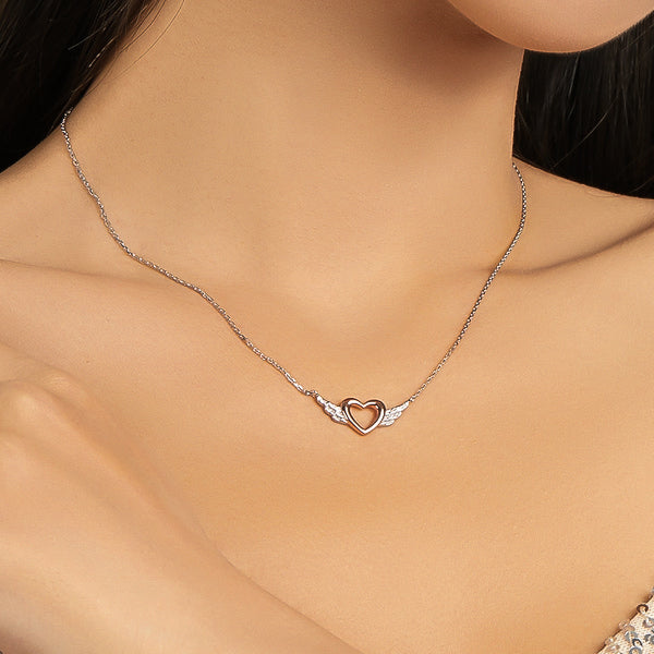Woman wearing a rose gold heart & silver wings necklace