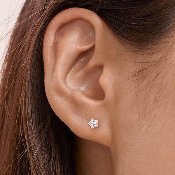 Woman wearing rose gold sparkling mini star stud earrings