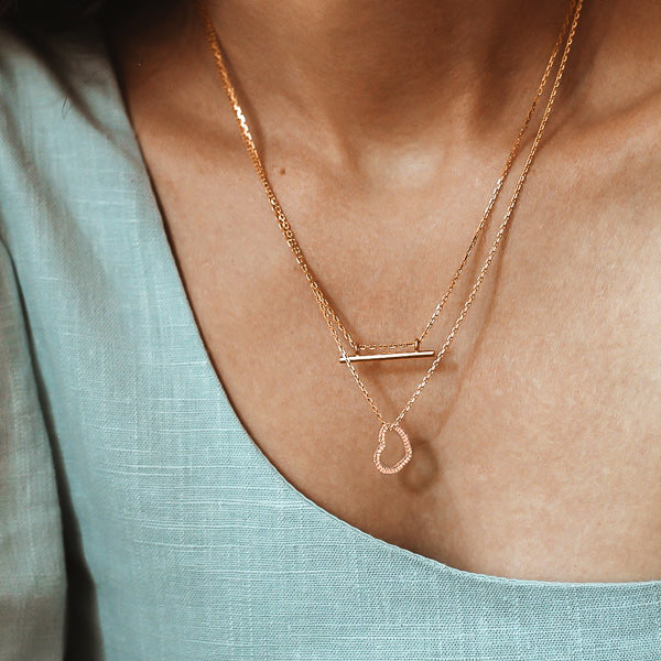 Woman wearing a rose gold twisted open heart pendant necklace