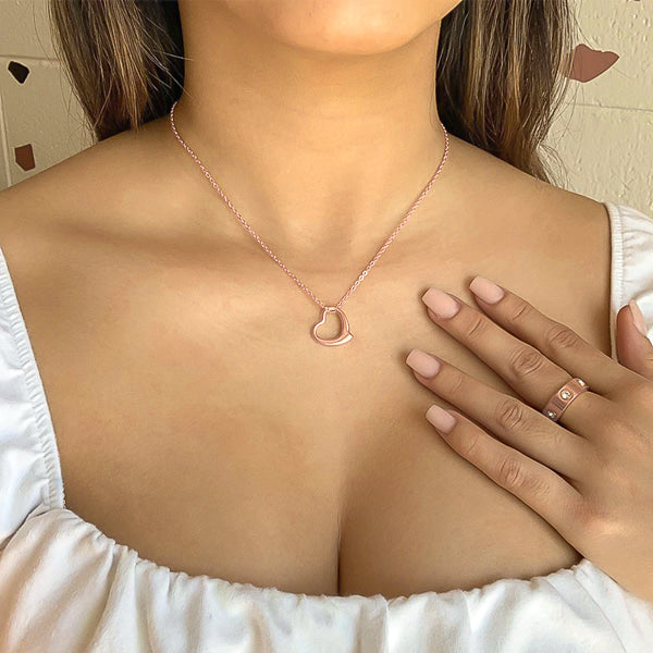 Woman wearing a rose gold wavy open heart pendant necklace