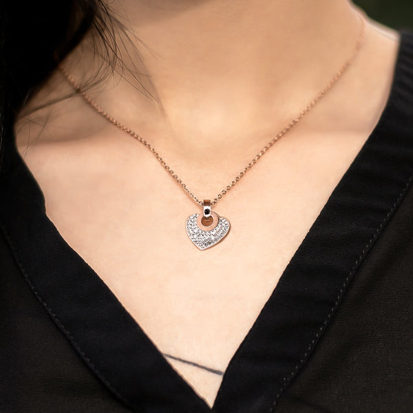 Woman wearing a white crystal heart pendant on a rose gold necklace