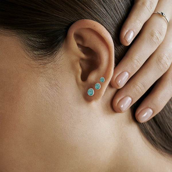 Woman wearing turquoise stone stud earrings