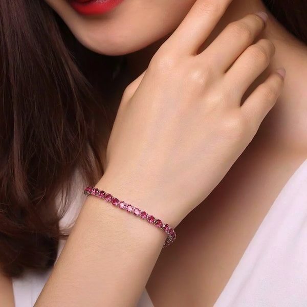 Ruby red cubic zirconia tennis bracelet on a woman's wrist
