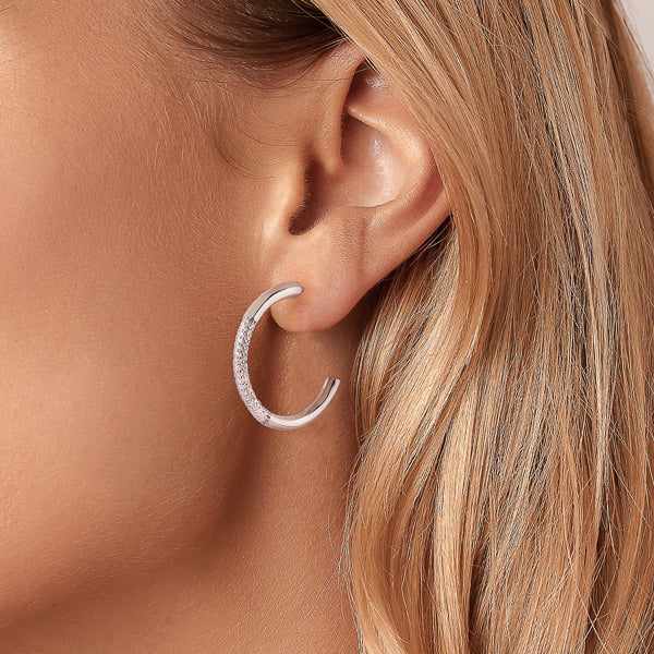 Woman wearing silver cubic zirconia pavé hoop earrings