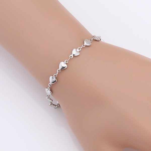Woman wearing a silver heart chain bracelet on her wrist