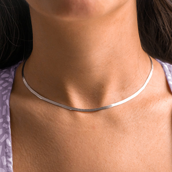 Woman wearing a silver herringbone choker necklace on her neck