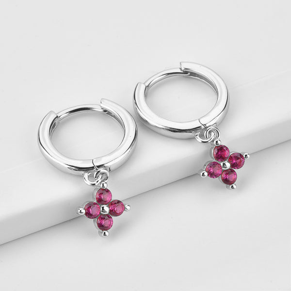 Silver huggie hoop earrings with a dangling pink cubic zirconia flower