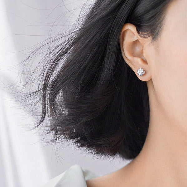 Woman wearing silver crystal rose flower earrings