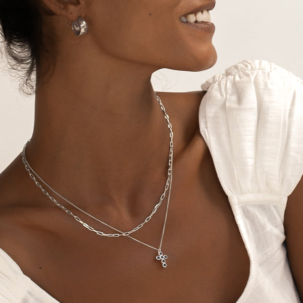 Woman wearing a silver rounded cross necklace with black crystals