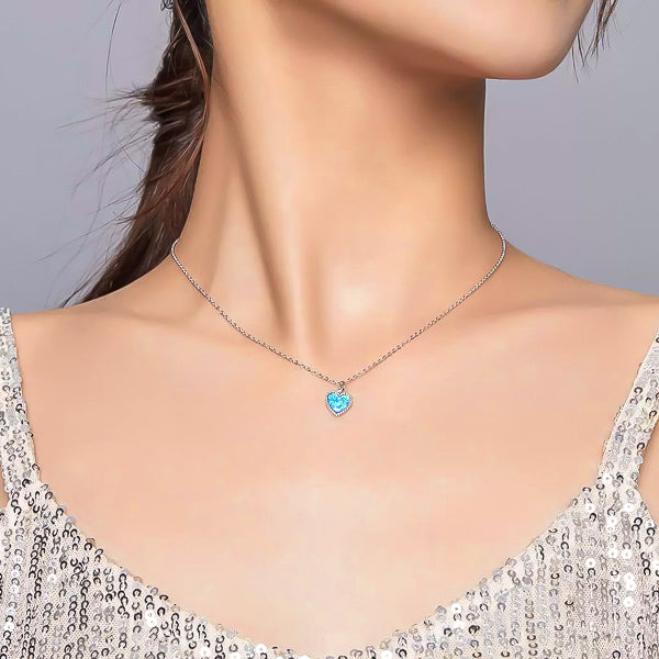 Woman wearing a silver necklace with a blue Opal heart pendant