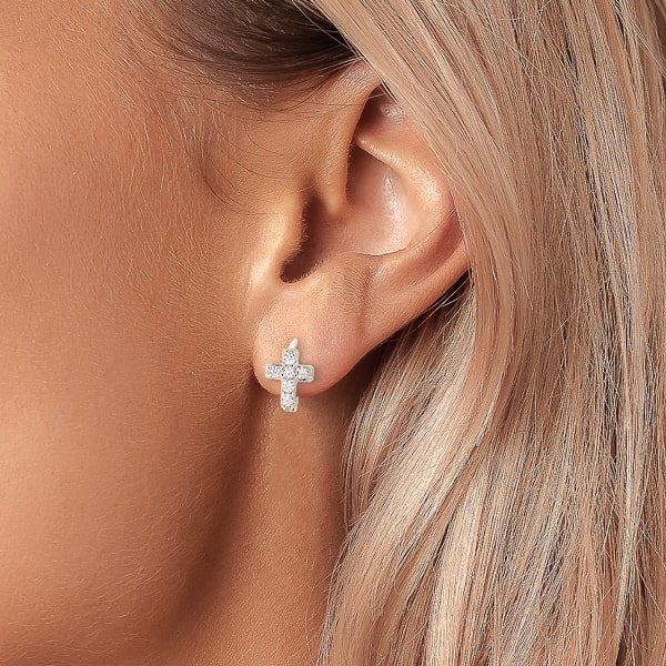 Woman wearing silver crystal cross huggie hoop earrings