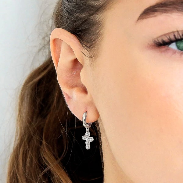 Woman wearing silver crystal cross mini hoop earrings