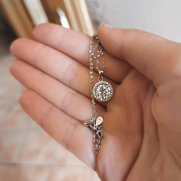 Silver crystal halo pendant necklace displayed on a hand
