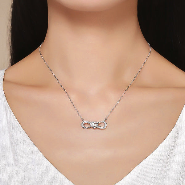 Woman wearing a silver infinity necklace with a heart knot and crystal trim