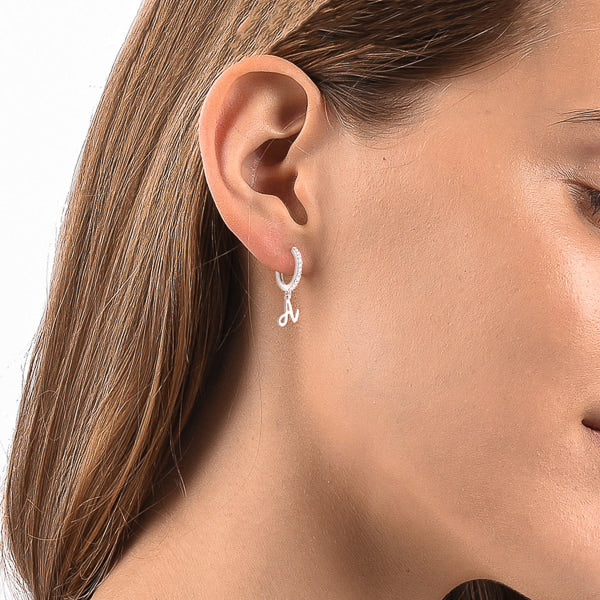 Woman wearing silver cursive initial letter earrings