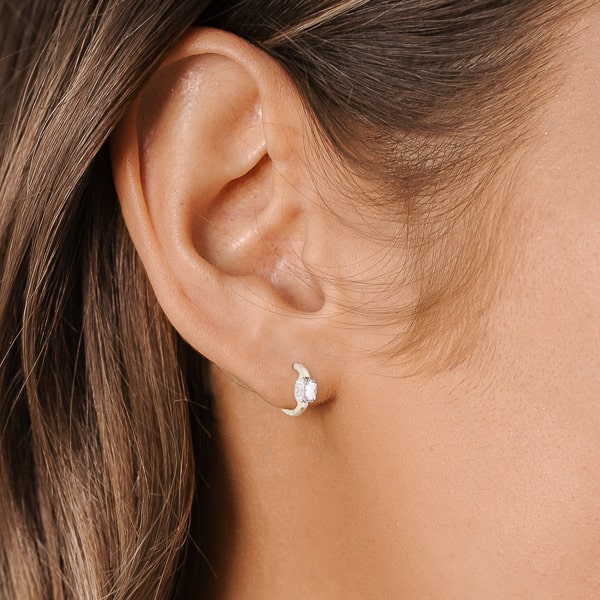 Woman wearing silver cushion-cut huggie hoop earrings