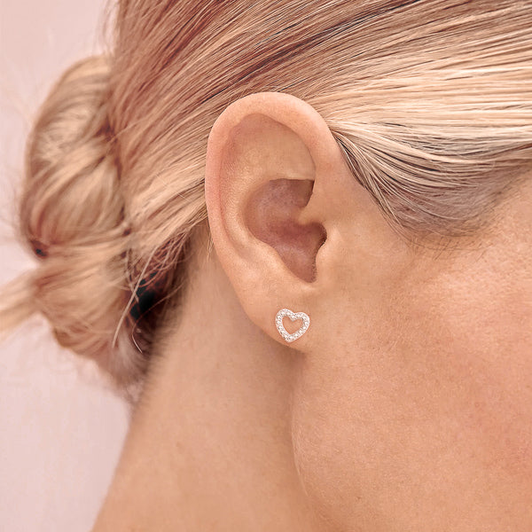 Woman wearing silver cubic zirconia open heart stud earrings