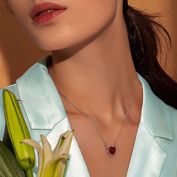 Woman wearing a red crystal devil heart on a silver necklace