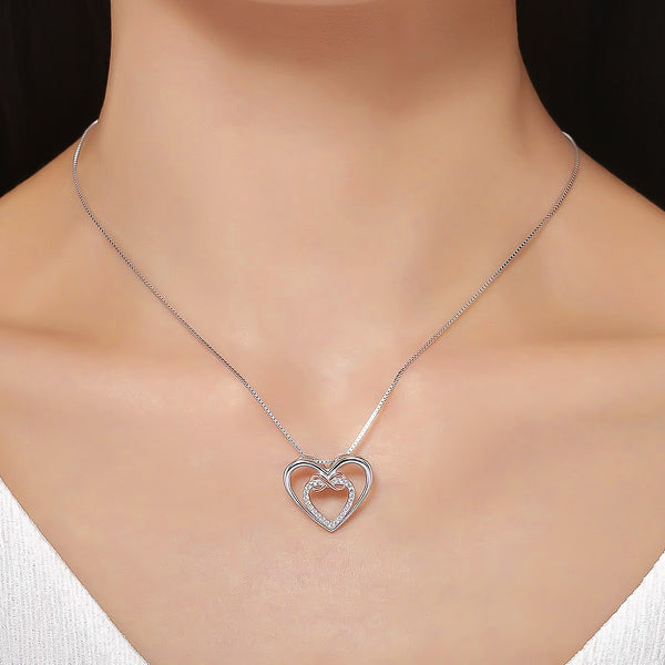 Woman wearing a dual heart pendant with an infinity symbol hanging form a silver chain