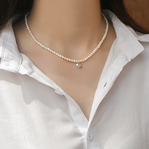 3-4mm freshwater pearl necklace with a silver heart on a woman's neck
