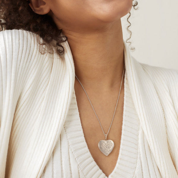 Woman wearing a silver heart locket pendant necklace