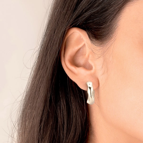Woman wearing silver irregular hoop earrings