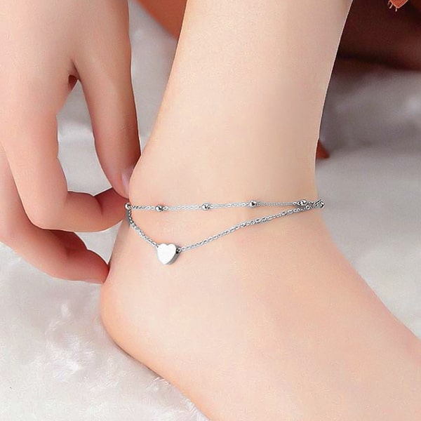 Silver layered beads and heart anklet on a womans ankle