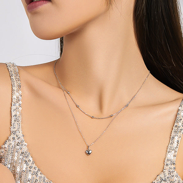 Woman wearing a silver layered heart & beads pendant necklace