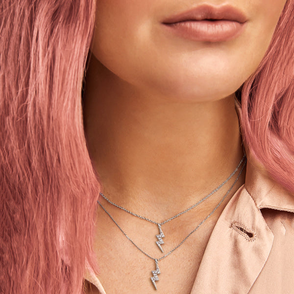 Woman wearing two silver lightning bolt necklaces