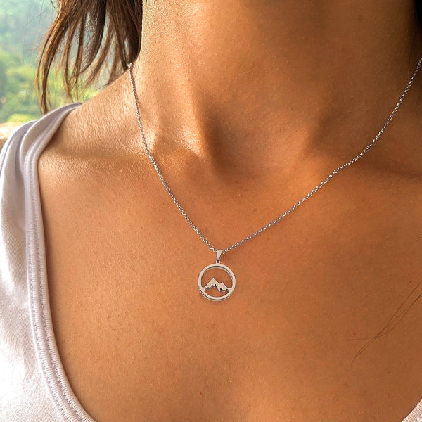 Silver mountain coin pendant necklace on a woman's neck