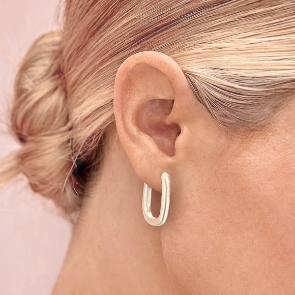 Woman wearing silver oval hoop earrings